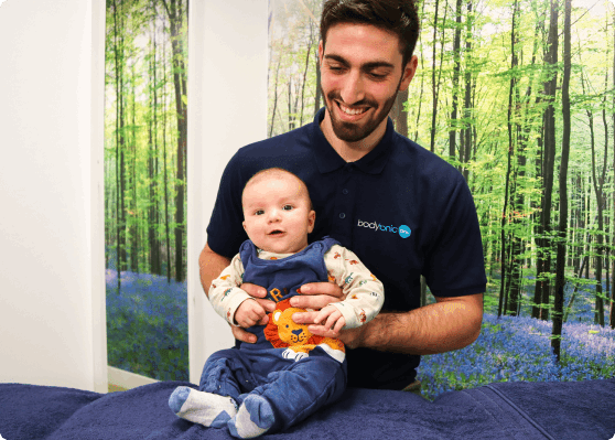 A bodytonic employee holding a baby.