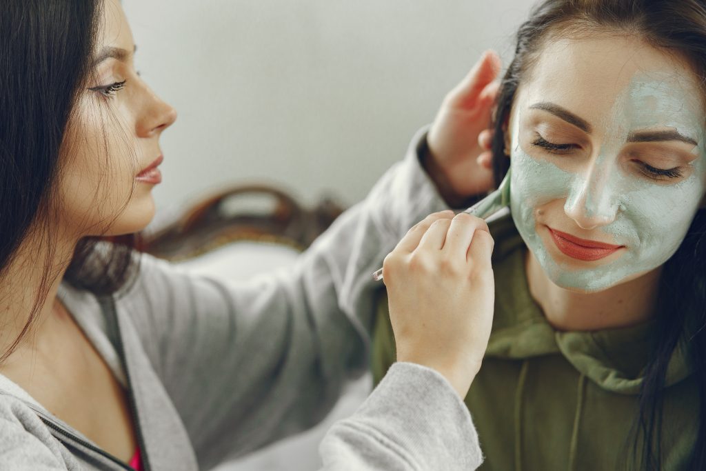 Lady applying a face mask to another lady