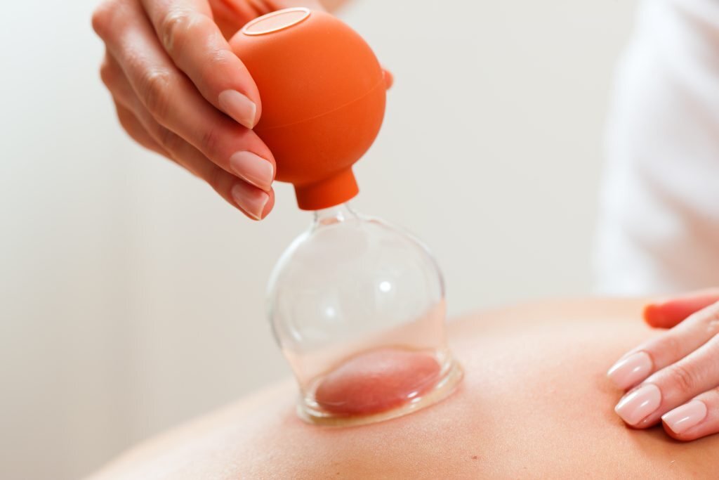 Close-up of cupping therapy with an orange suction cup on the skin.