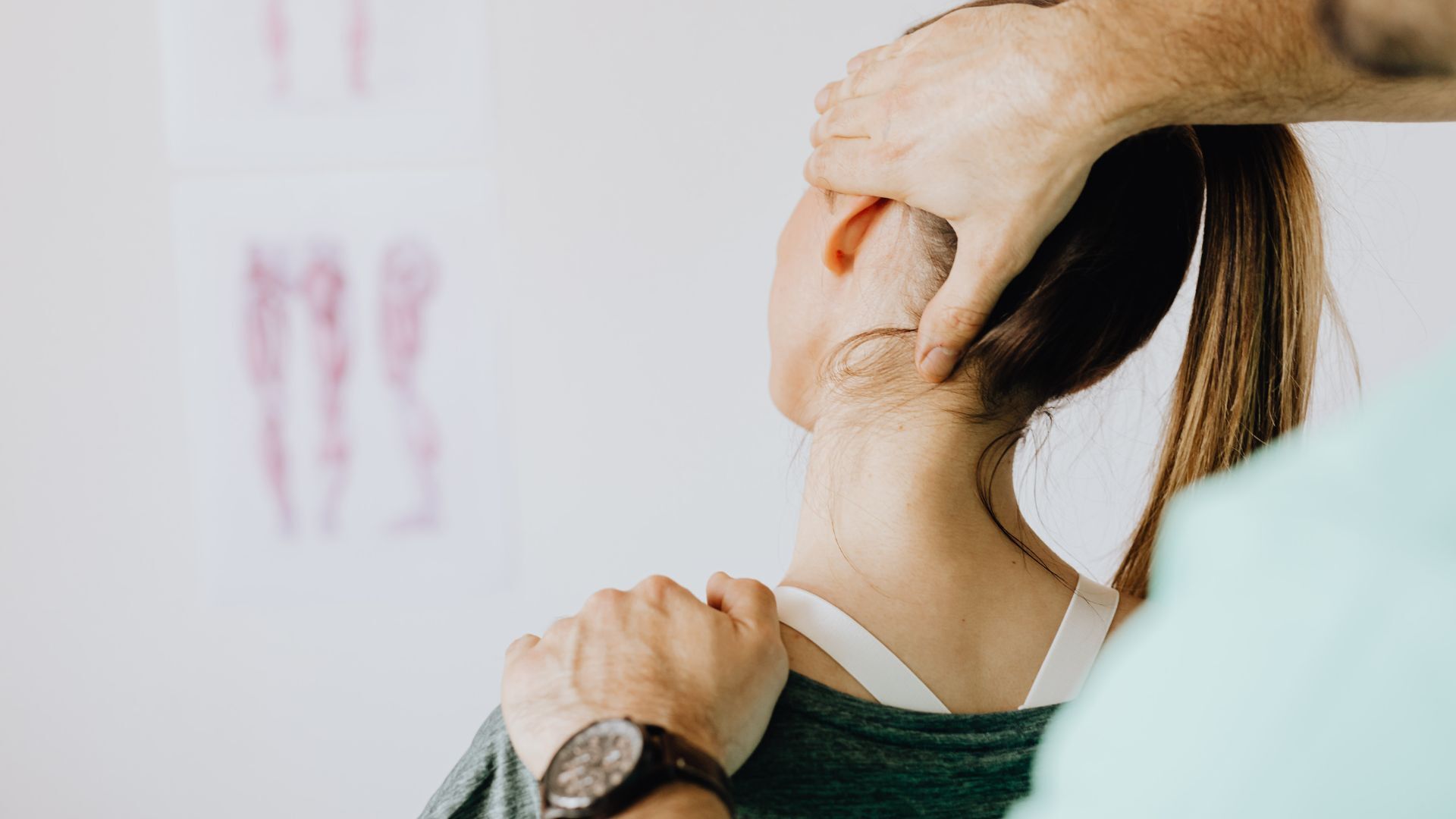 A Chiropractor performing a neck adjustment on a woman with a ponytail in a clinic setting.