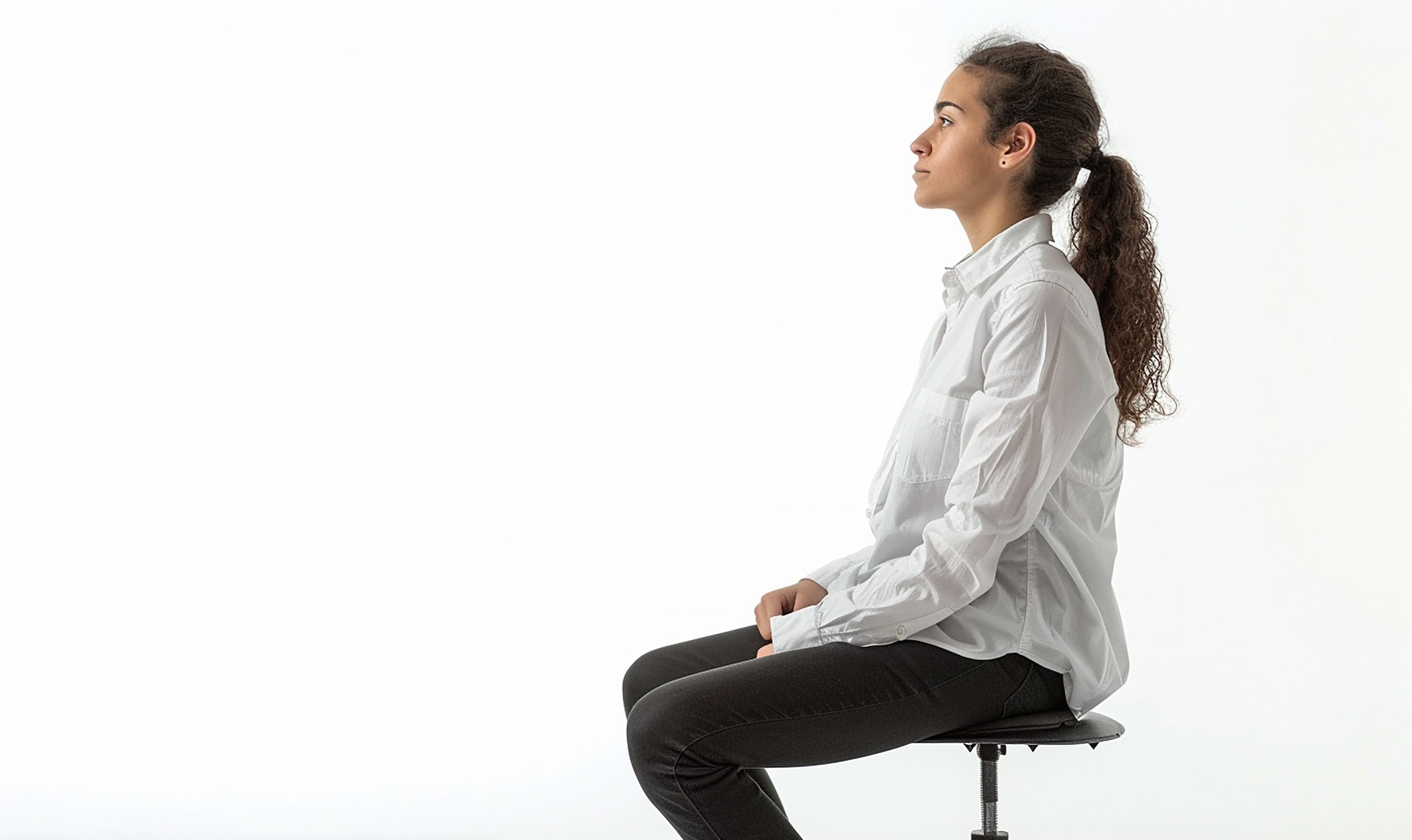 woman sits stool with her hair ponytail scaled Top 10 Benefits of Booking a Chiropractor Appointment