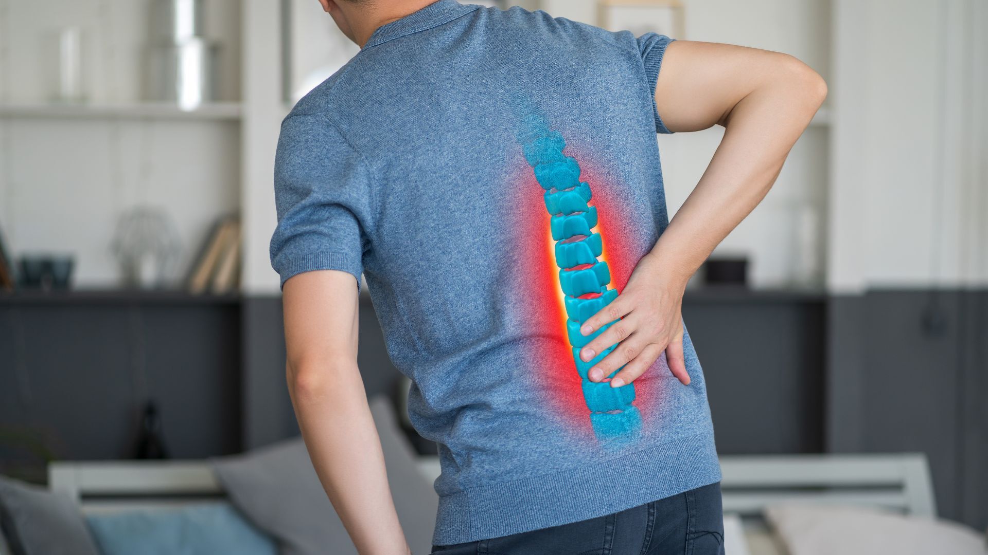 A man in a blue shirt experiencing lower back pain, with a digitally enhanced spine illustration highlighting the affected area.