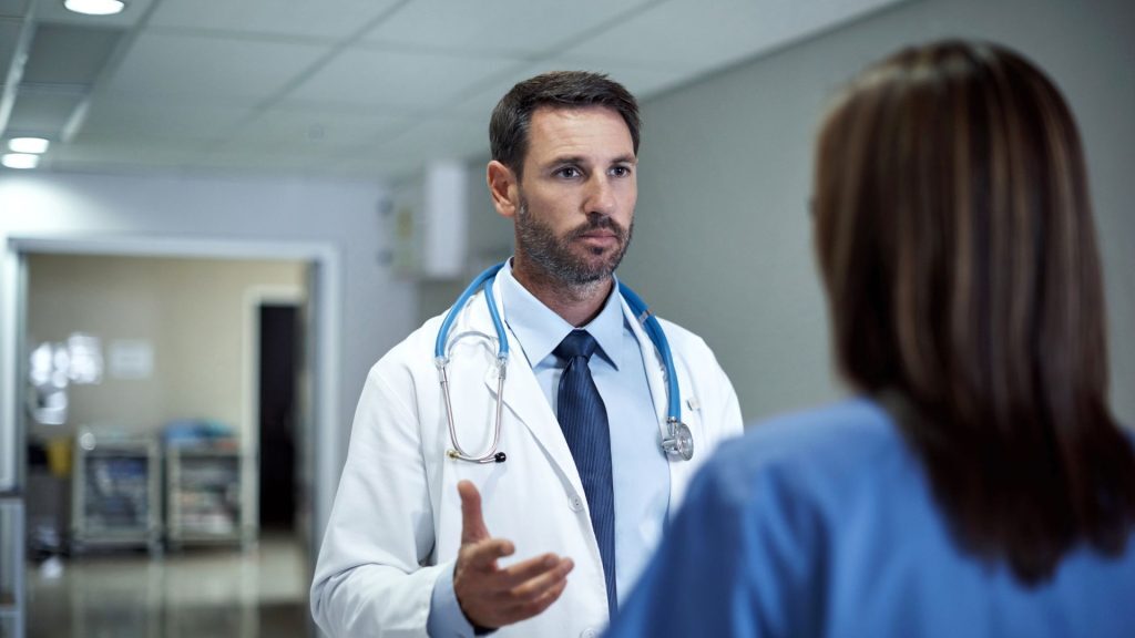 Doctor talking to a patient in a hospital hallway.