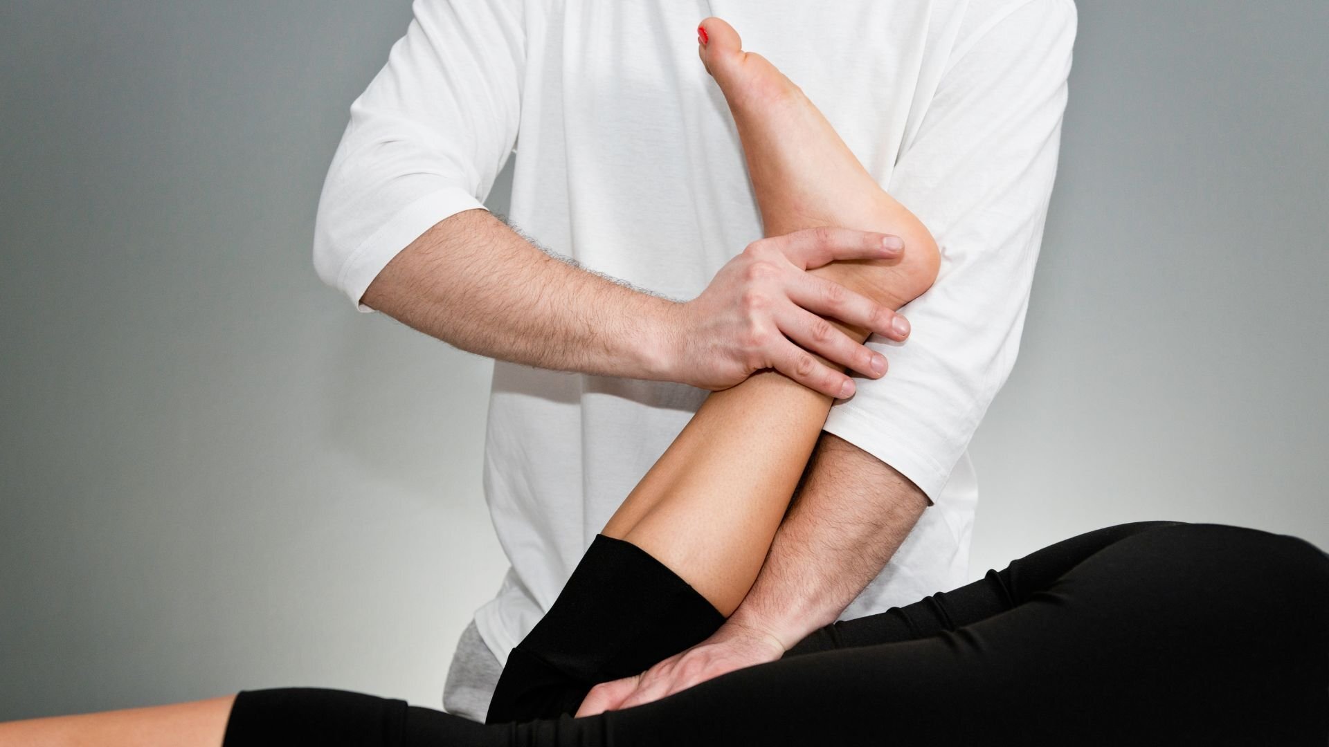 Physiotherapist performing a leg stretch on a patient lying down, focusing on improving mobility and flexibility through assisted movement.