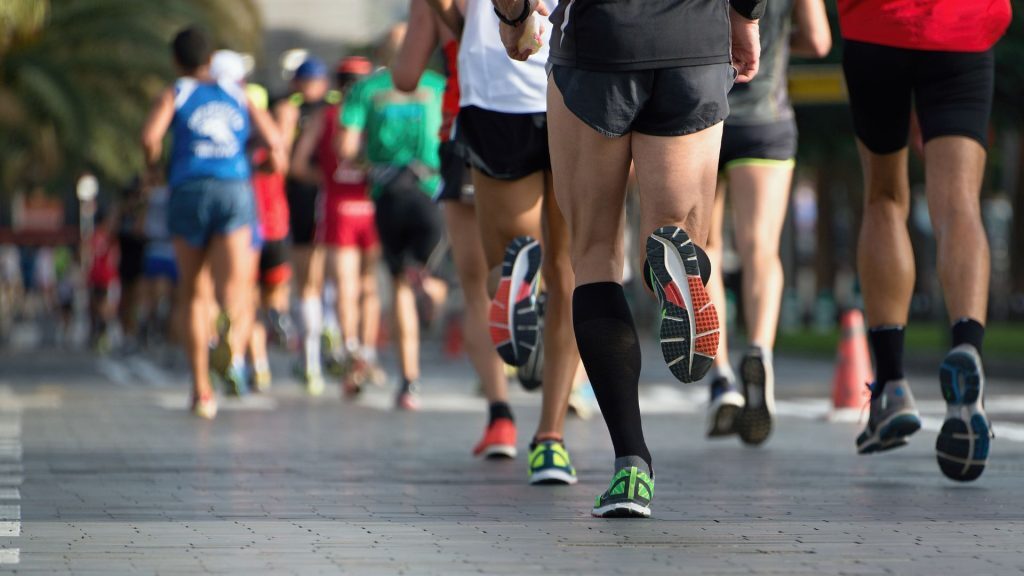 Close-up of a group of runners from behind during a road race, highlighting lower leg movement and athletic footwear.