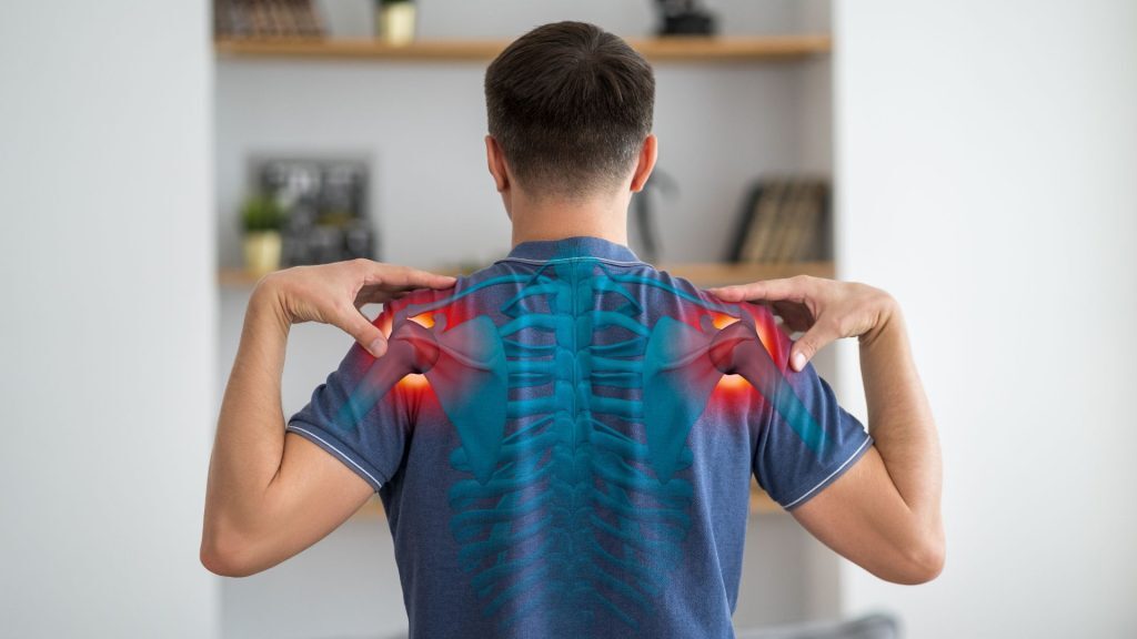 Man holding his shoulders with a highlighted spine and shoulder anatomy overlay.