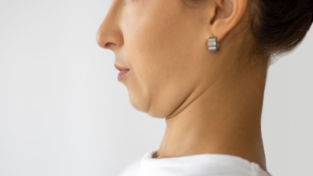Close-up side view of a woman performing a chin tuck exercise.