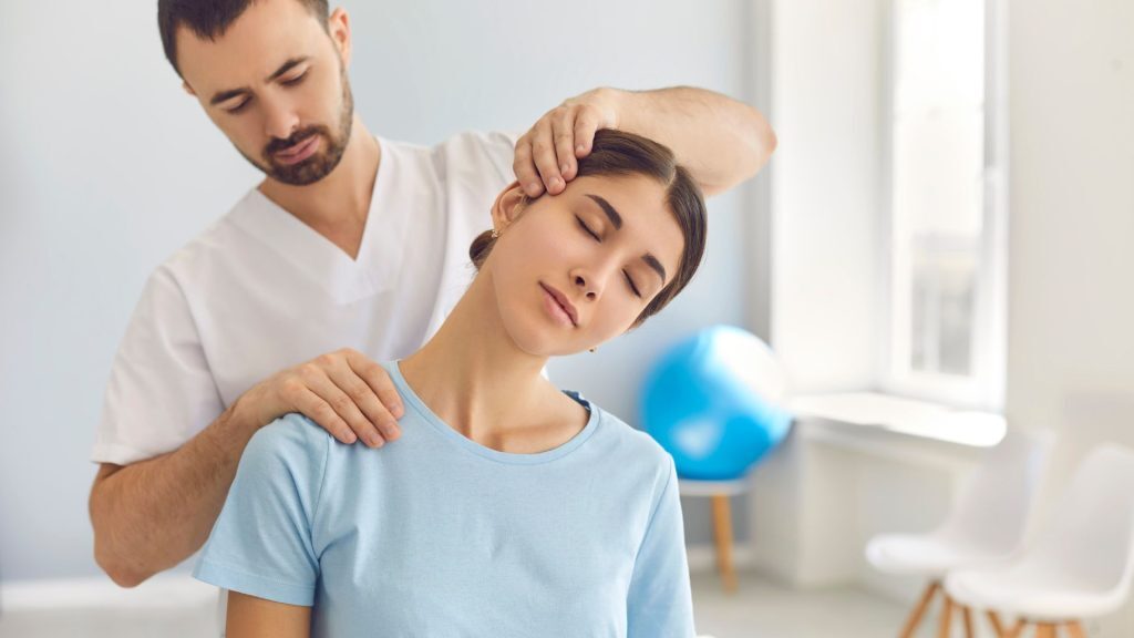 Physiotherapist performing neck manipulation on a female patient during a migraine physiotherapy session in a bright clinical setting.